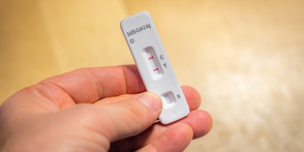 man of a man holding a positive covid-19 auto test