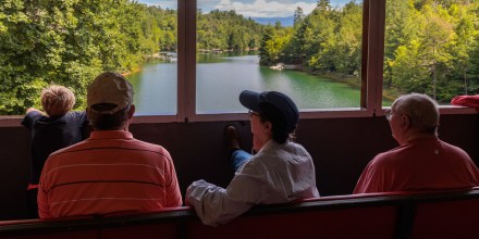 passengers looking out the windows of the open air train car