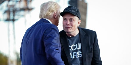 Elon Musk and Donald Trump shake hands on stage outside