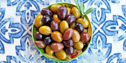 Assortment of fresh olives on a plate. Blue background.