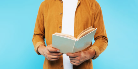 cropped image of man holding open book isolated on blue