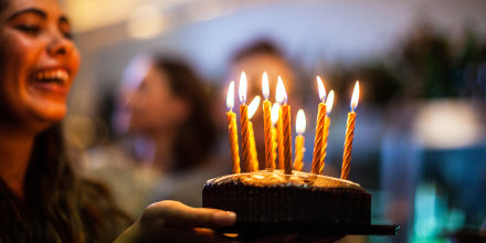 Friend golding birthday cake with candles.