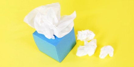 Blue tissue box with crumpled tissues beside it