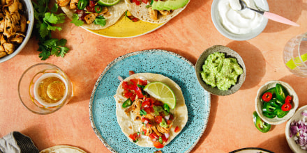Top view shot of tacos with filling ingredients around on table.