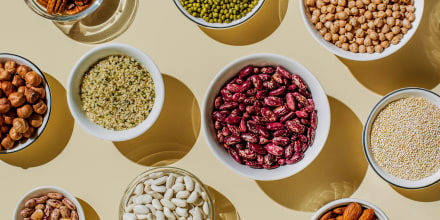 Various kinds of vegan protein sources on beige background. Set of food supplements. Gluten free cereals as ground hemp seeds, quinoa. Nuts and legumes (green mung beans, chick-pea, red lentil, kidney bean, almonds, hazelnuts). Flat lay, top view