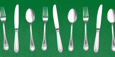 Forks, knives, and spoons lined up against a green background.