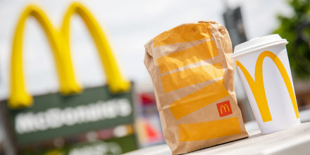 A McDonald's to-go bag and cup in front of a McDonald's.