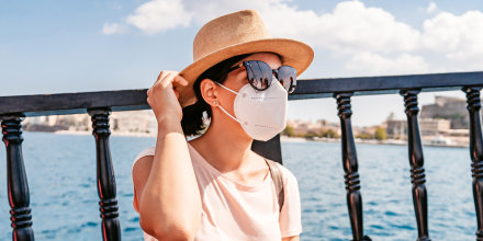 Young woman wearing a mask outdoors in summer.