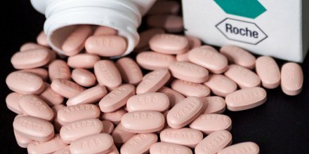 Pink pills are grouped onto a black surface