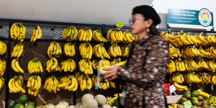 A shopper in front of a display of bananas.