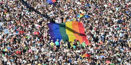 Crowd holding a Pride flag during the parade.