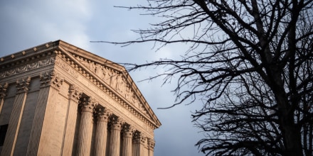 The exterior of the Supreme Court building on the left, a tree is seen on the right