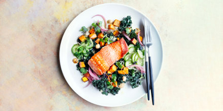 Plate of roasted salmon with leafy greens and sweet potato.