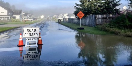 Cones and a road closed sign on a flooded residential street
