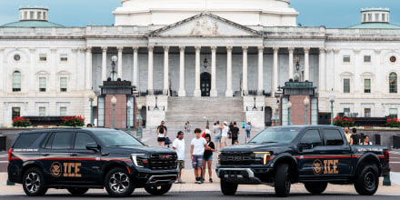 People look at  An Immigration and Customs Enforcement (ICE) branded GMC SUV and an Immigration and Customs Enforcement (ICE) branded Ford pickup truck parked at the Capitol 