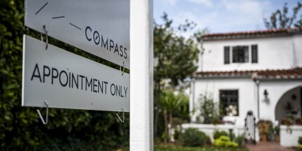 A Compass sign that reads "Compass, Appointment Only" outside of a white house