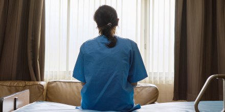 A young woman sits alone in a hospital room.