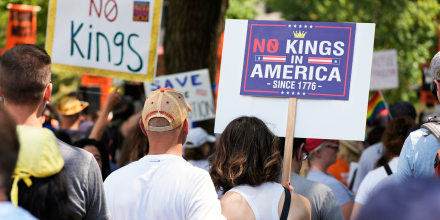 Activists carry signs during a "No Kings" protests.