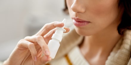 close up of sick woman using nasal spray