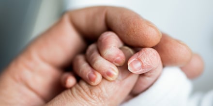 hand of newborn baby who has just been born holding the finger of his father's hand.