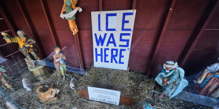 An "ICE WAS HERE" sign over an empty manger at a Nativity scene 