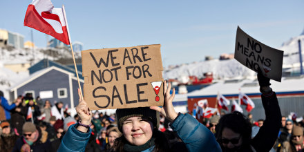 A protester holds a sign outside reading 'We are not for sale'