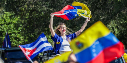 People wave Venezuelan flags outside