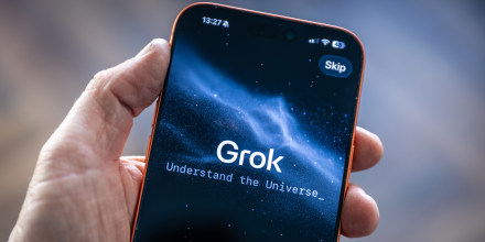 A hand holds a smartphone with the Grok app opened on the screen
