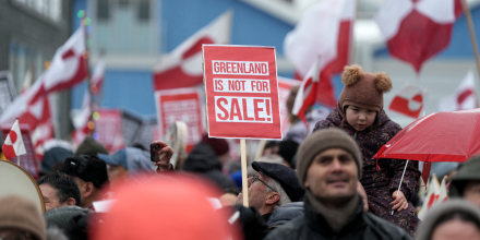 Gente en la capital groenlandesa, Nuuk, sostiene banderas locales y carteles que dicen "Groenlandia no está a la venta" en protesta contra amenazas del estadounidense Donald Trump, el 17 de enero de 2026.