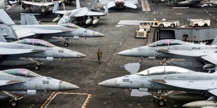A US Navy officer walks past fighter jets parked on the flight deck of the Nimitz-class aircraft carrier USS Abraham Lincoln