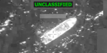 A grainy, black and white satellite image shows the rough outline of a boat in the water.