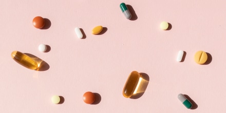 Top view of various pills and tablets on the pink background