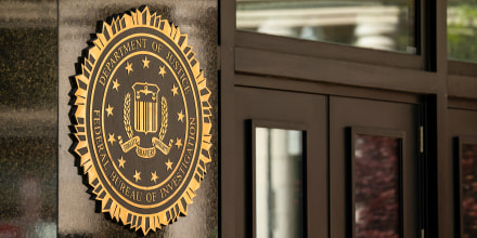 The exterior of a government building with the DOJ seal on its facade.