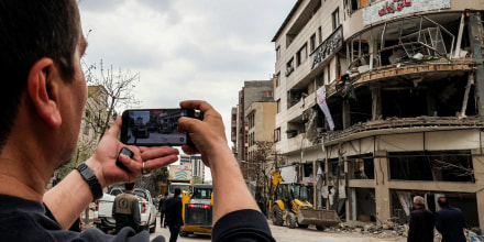 A man films with a phone from the street the destruction on an office building