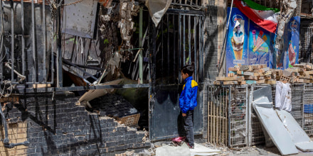 A boy peers into a damaged residential building.