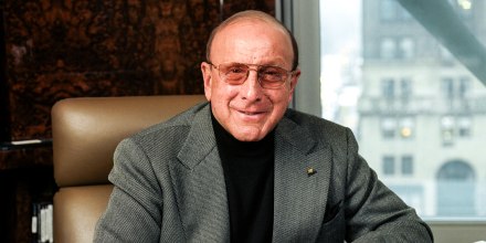 Clive Davis sits at a desk in an office by a window