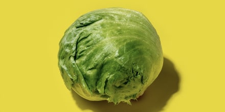 Fresh Iceberg lettuce on a bright solid yellow background.