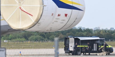 Police forensic technicians prepare to deploy an explosive-disposal robot near an aircraft. 