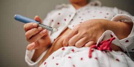 Low angle view of woman injecting insulin into abdomen with blue pen, daily diabetes treatment and home healthcare routine