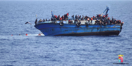 Image: Migrants are seen on a capsizing boat before a rescue operation by Italian navy ships \"Bettica\" and \"Bergamini\" (unseen) off the coast of Libya