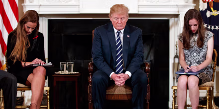 Image: President Donald Trump, joined by student Carson Abt, right, and Julia Cordover, the student body president at Marjory Stoneman Douglas High School bow their heads during the opening prayer
