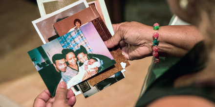 Maria Velazquez holds a stack of family photos in her hands. One of the photos shows her son, JJ Velazquez, smiling with his then-girlfriend, Vanessa Cepero, and their two sons.