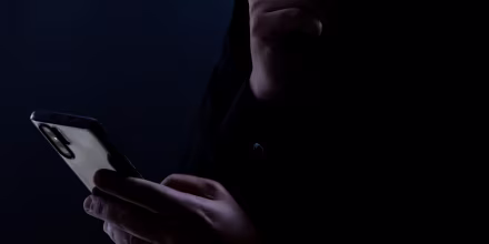 Silhouette of a man using a mobile phone in the dark