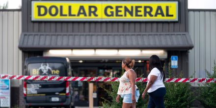People walk past the Dollar General store where three people were shot and killed the day before in Jacksonville, Fla. on Aug. 27, 2023. Police say that the attack by a gunman on Black customers at the store that killed three is being investigated as a hate crime.
