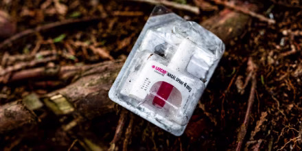 A container of Narcan, or naloxone, sits on tree roots 
