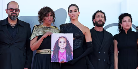 From left, standing next to one another, Amer Hlehel, Kaouther Ben Hania (holding an image of Hin Rajab), Saja Kilani, Motaz Malhees, and Clara Khoury