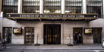 A brick building with tall windows and an awning with lettering: CHURCH OF SCIENTOLOGY OF NEW YORK.