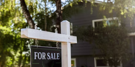 Image: Image of a real estate for sale sign posted in front of a residential home
