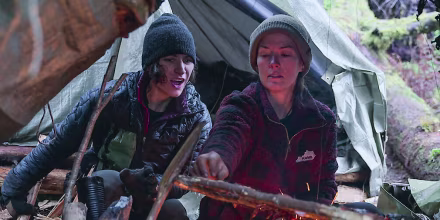 Amber Asay, left, and Jill Ashock light a fire outside while sitting underneath a tent