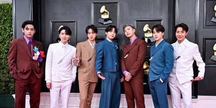 From left, V, Suga, Jin, Jungkook, RM, Jimin and J-Hope stand on the red carpet in different colored suits